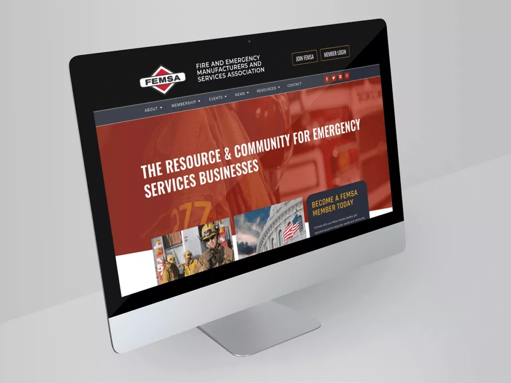 A computer monitor displays the FEMSA website, featuring information and resources for emergency services businesses, with images of firefighters and a prominent red banner.