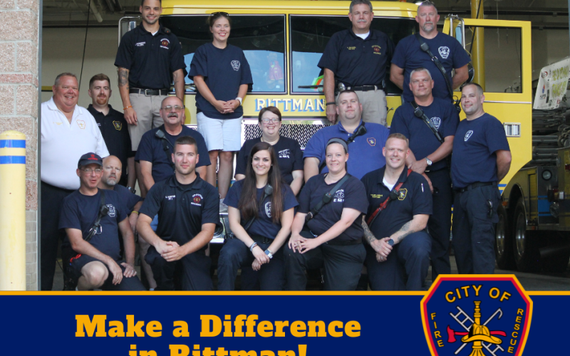 A group of firefighters and volunteers pose in front of a yellow fire truck. Text below reads: "Make a Difference in Rittman! Learn more about our volunteer opportunities!" A City of Rittman Fire & Rescue emblem is shown.